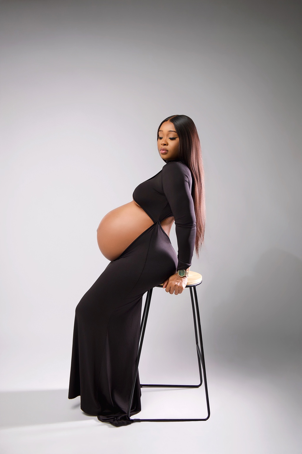 Expecting mother in a black dress in the studio