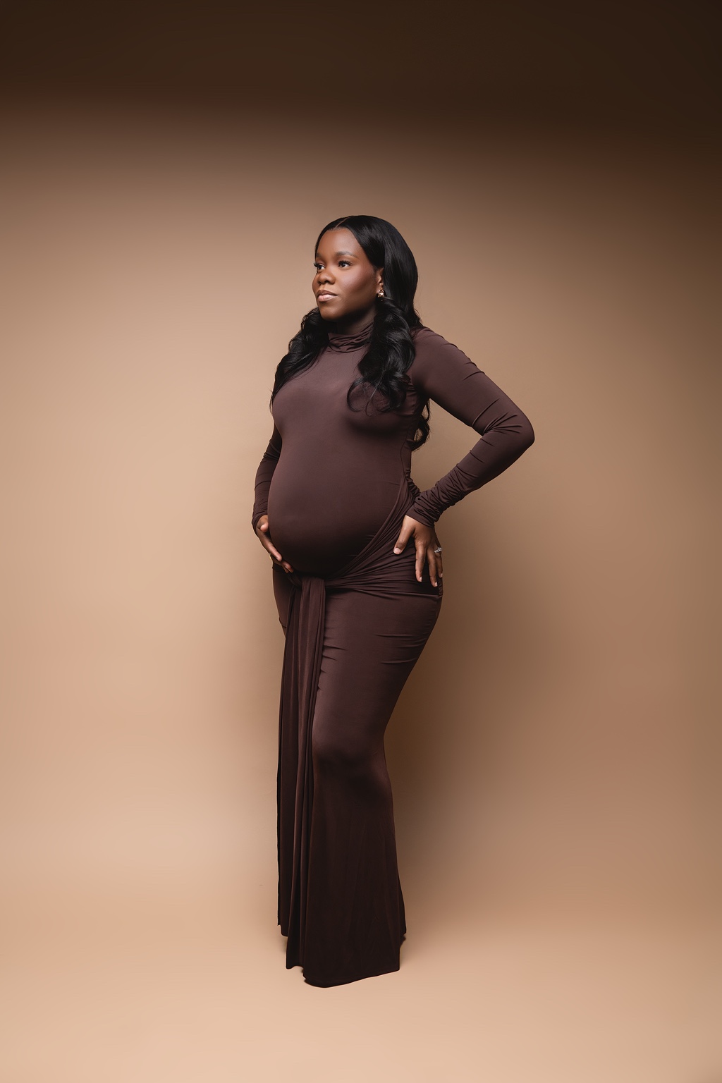 Expecting mother standing in a brown fitted gown