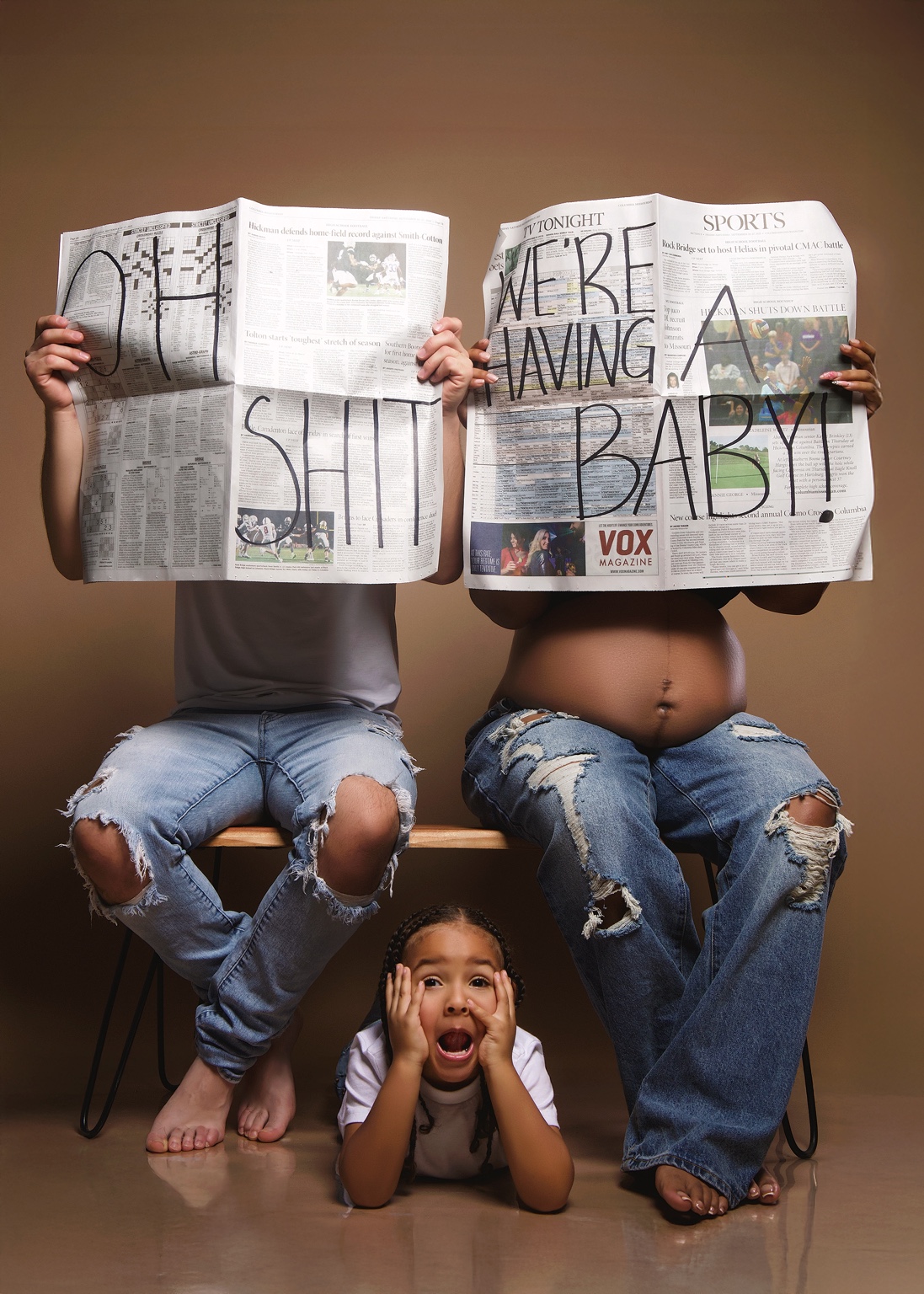 Expecting family announcing their new baby with newspaper props